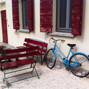 Blaues Fahrrad an Hauswand mit roten Fensterläden